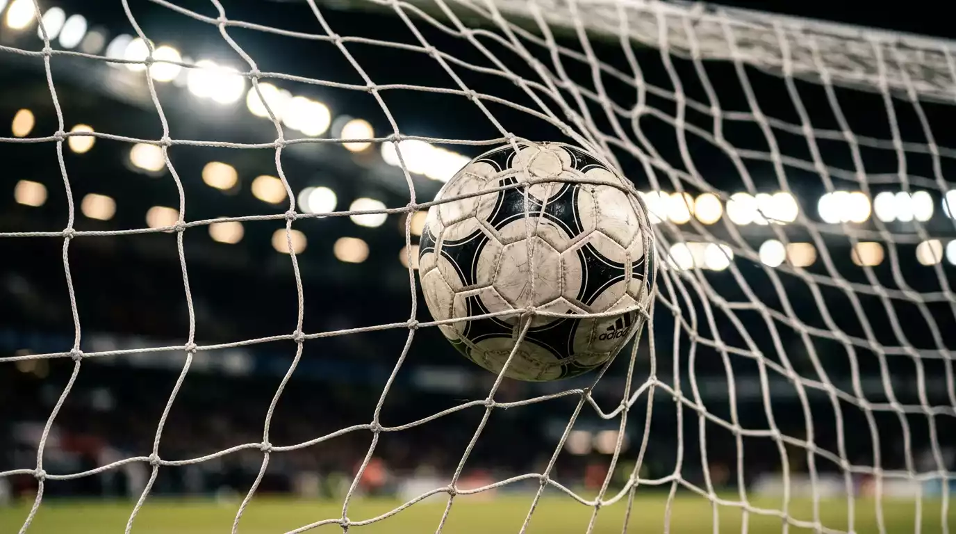 Jalkapallo maaliverkossa ja stadionin valot taustalla